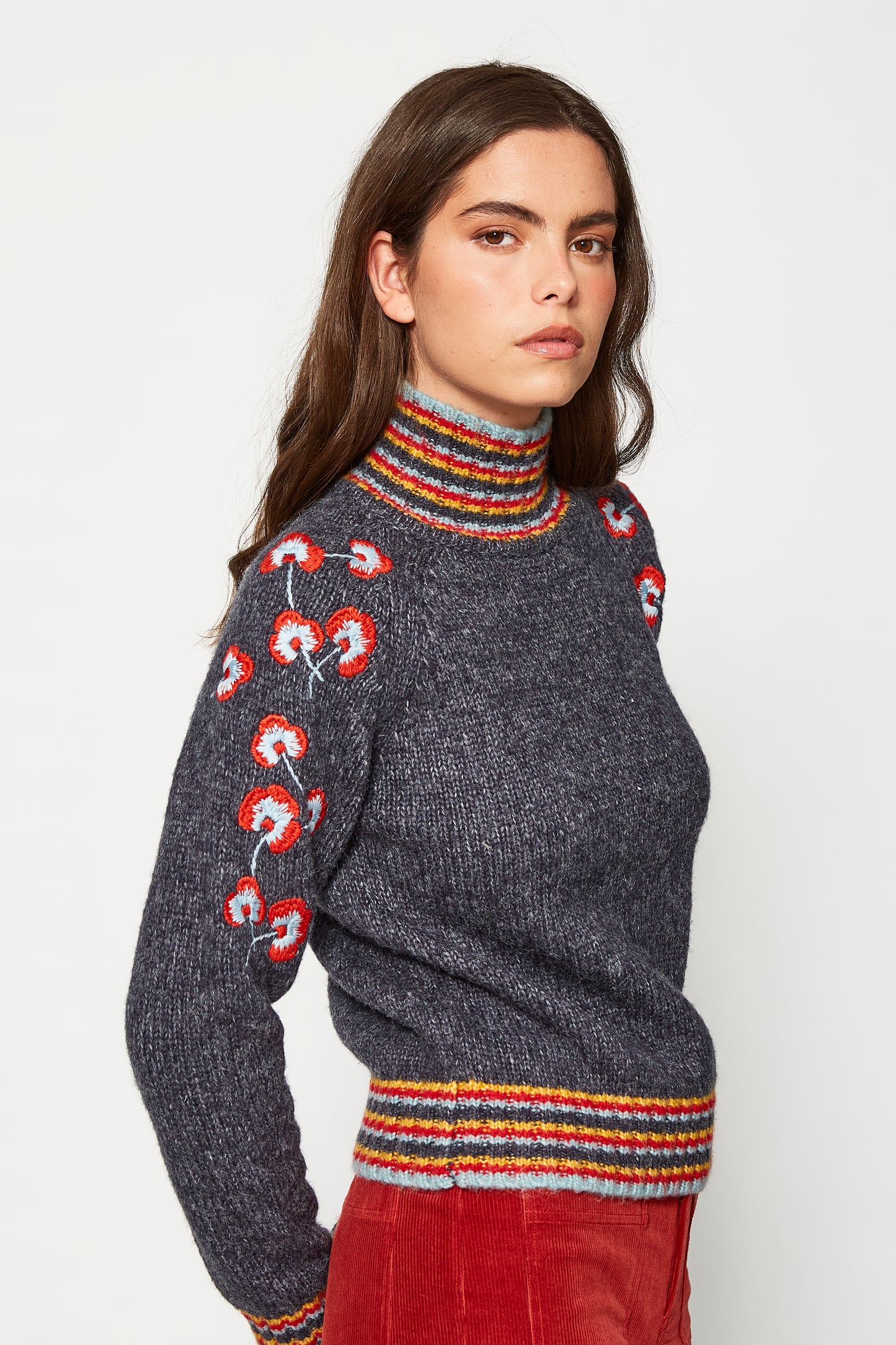 Woman wearing a dark gray sweater with colorful floral patterns on a white background