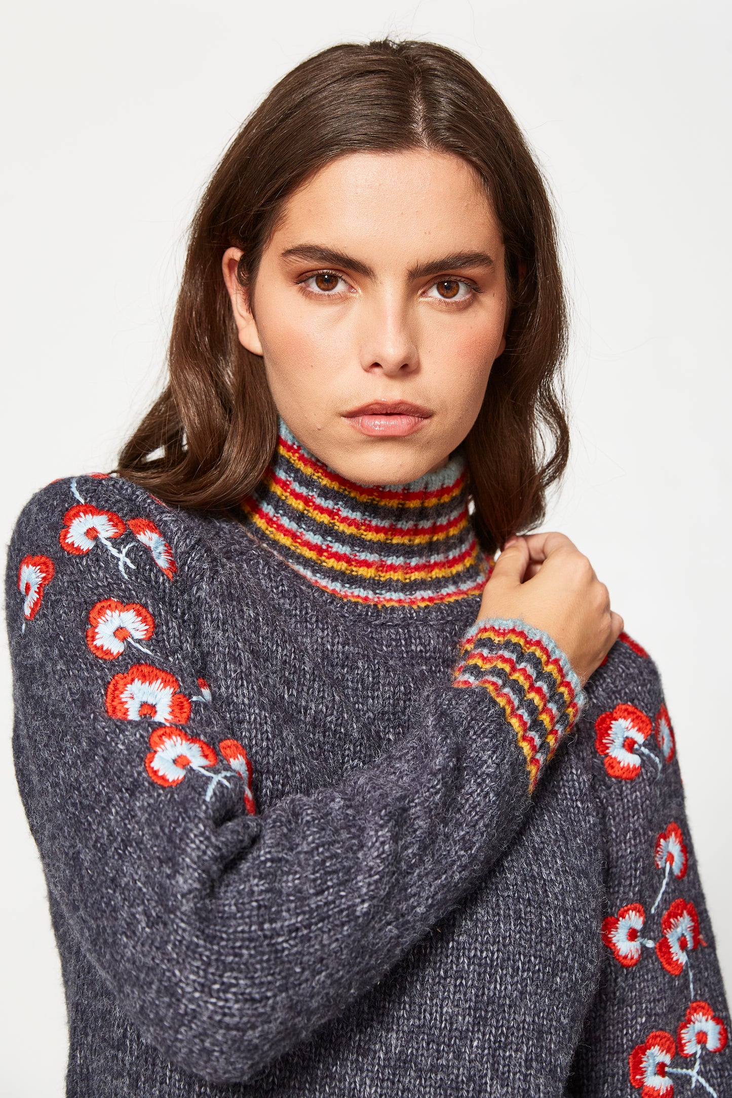 Woman wearing a gray sweater with colorful patterns on a white background