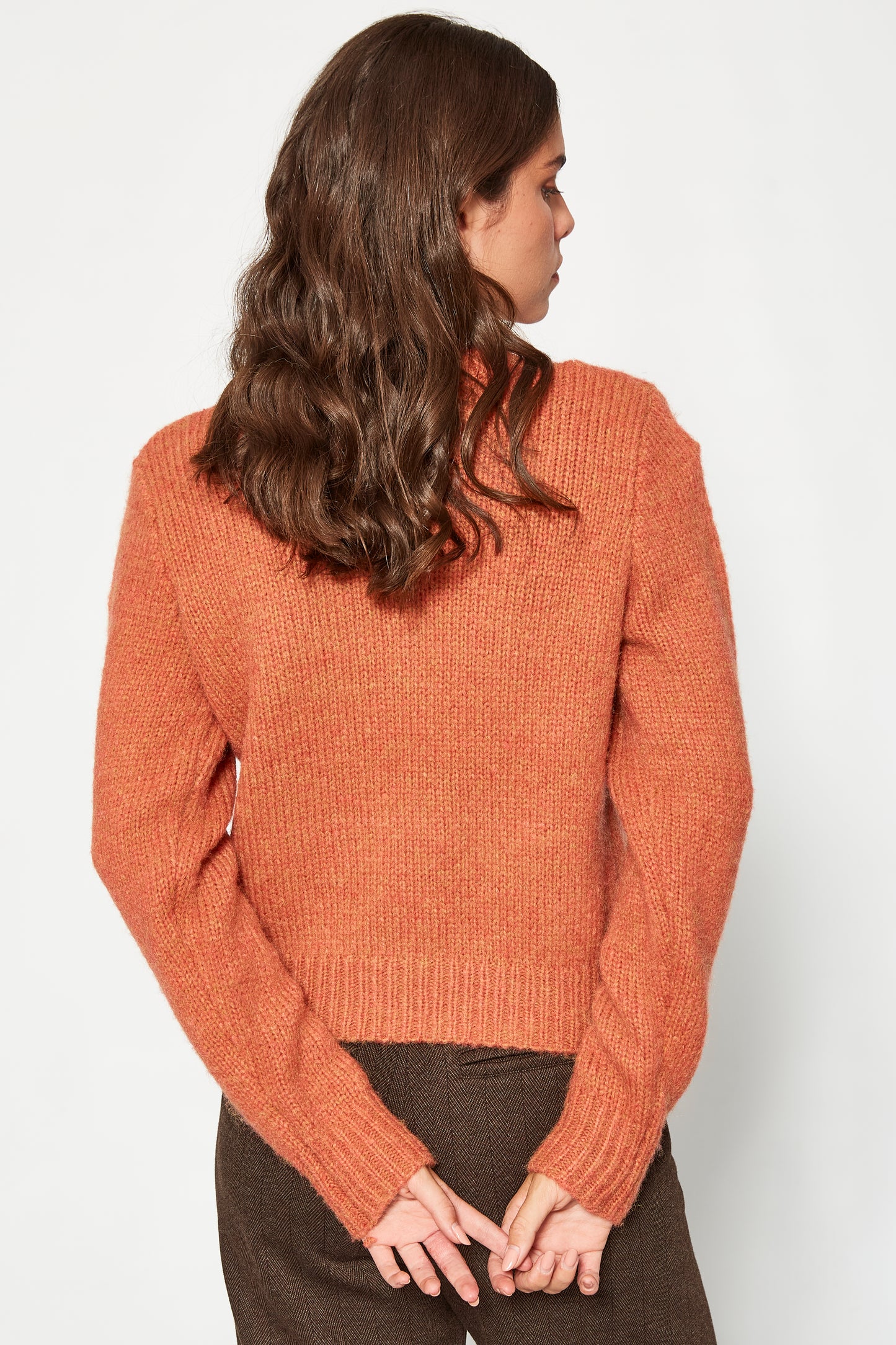 Woman wearing a rust-colored sweater against a white background
