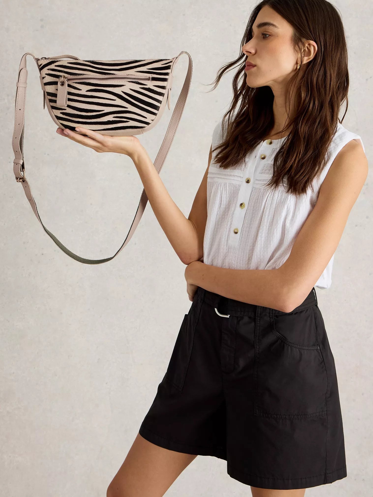 the Caro Crossbody Bag from White Stuff. Its crescent shape is updated for a modern twist. You'll be delighted by the multitude of zippered pockets and an adjustable strap for the perfect fit. Plus, who can resist the abstract zebra print in luxurious calf hair?
