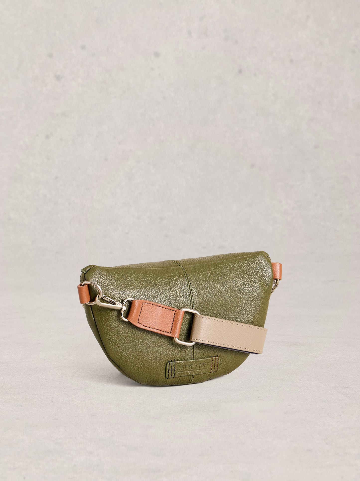 Green leather crossbody bag with a beige strap on a light gray background