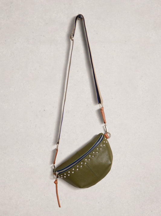 Green crossbody bag with studded details on a light gray background