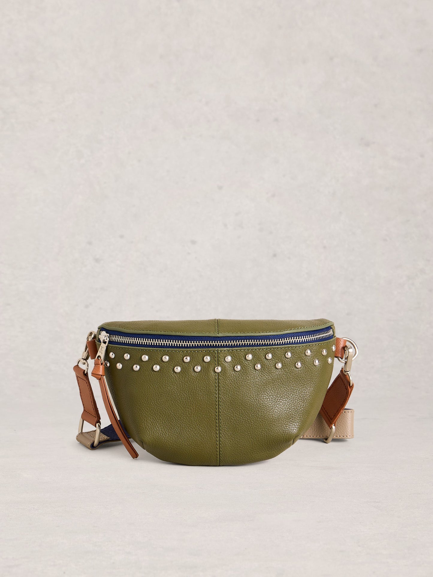 Green leather bag with studded details on a light gray background
