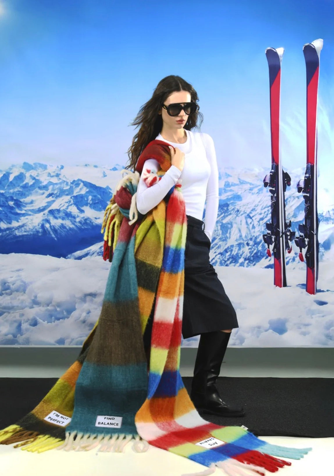 Person holding a colorful scarf with skis in the background