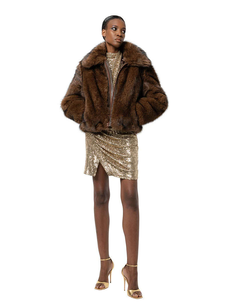 Woman wearing a fur coat and gold sequin dress on a white background