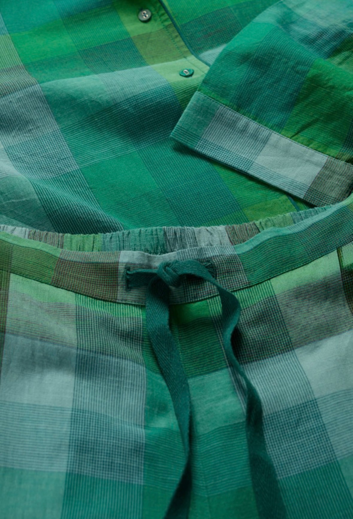 Close-up of a green plaid shirt with a tie, focusing on the collar and tie area.