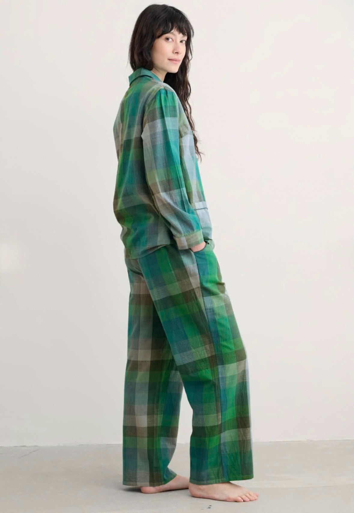 Person wearing green plaid pajamas on a white background