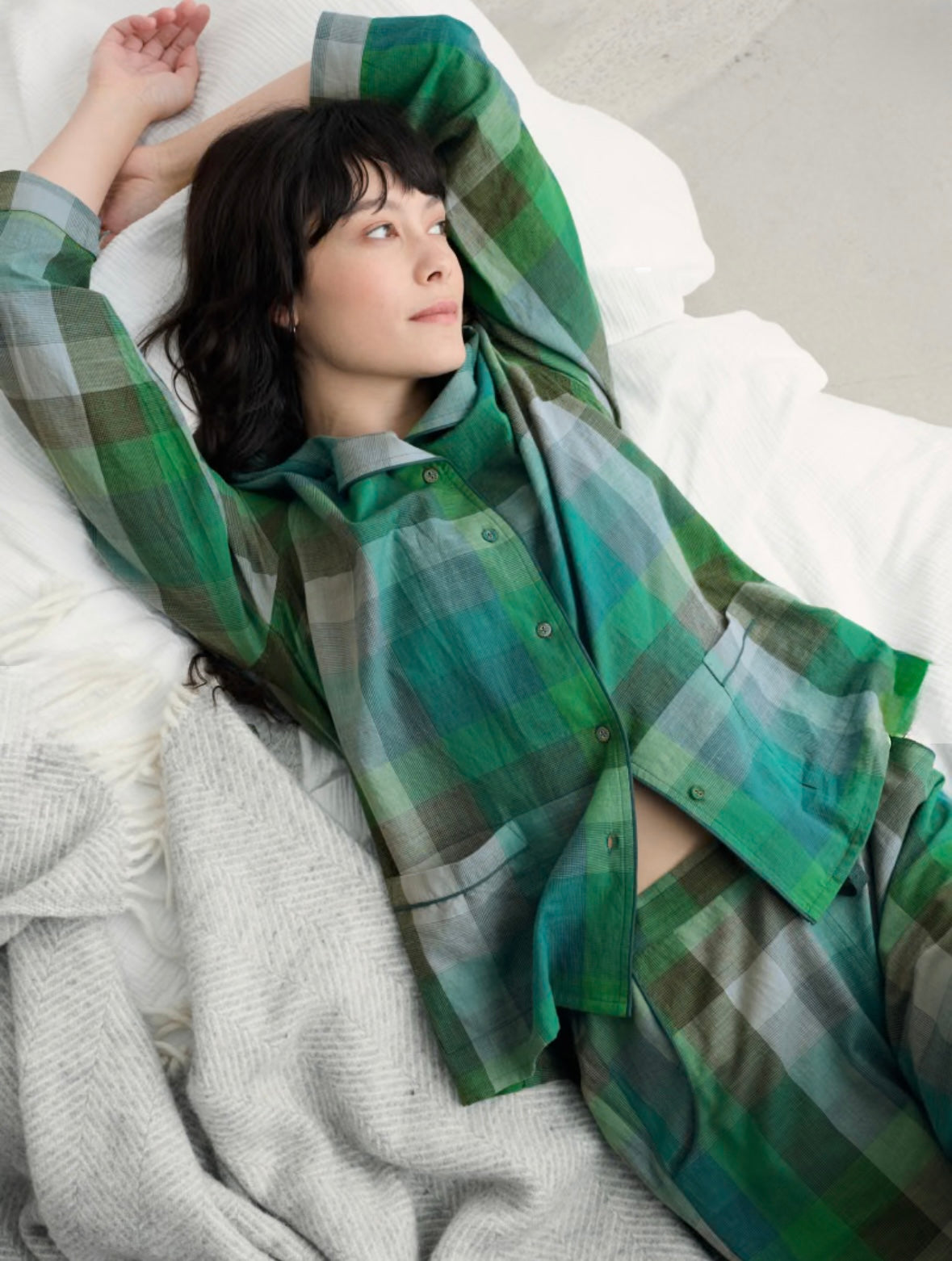 Person wearing a green plaid shirt lying on a white surface