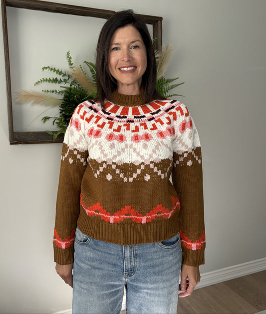 Woman wearing a patterned sweater standing indoors with a neutral background