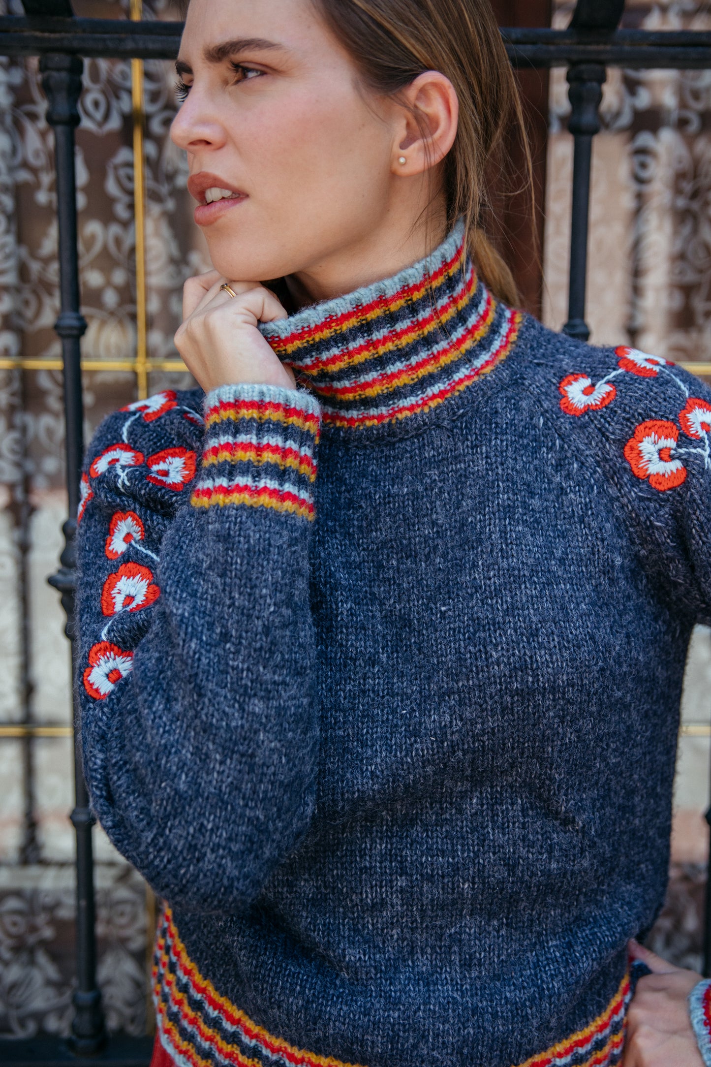 Woman wearing a blue sweater with colorful patterns in an outdoor setting
