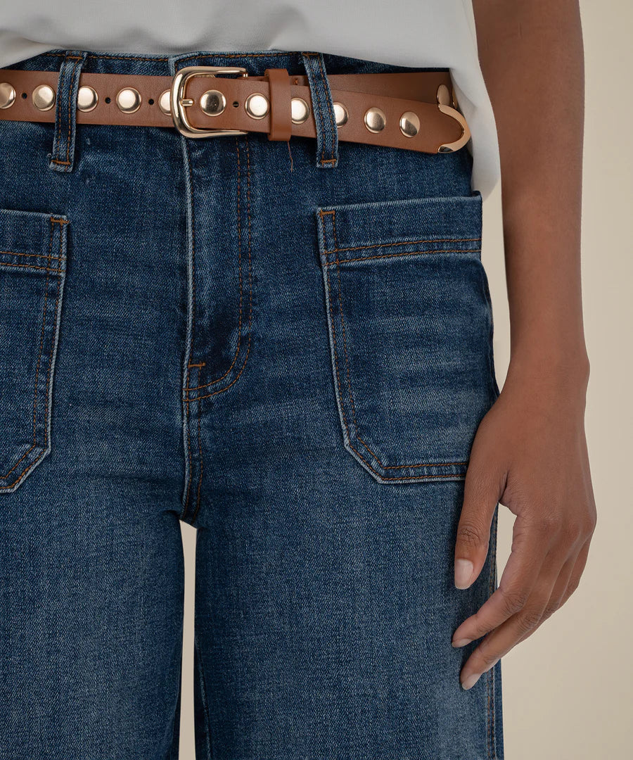 Close-up of blue jeans with a brown belt and gold buckle.