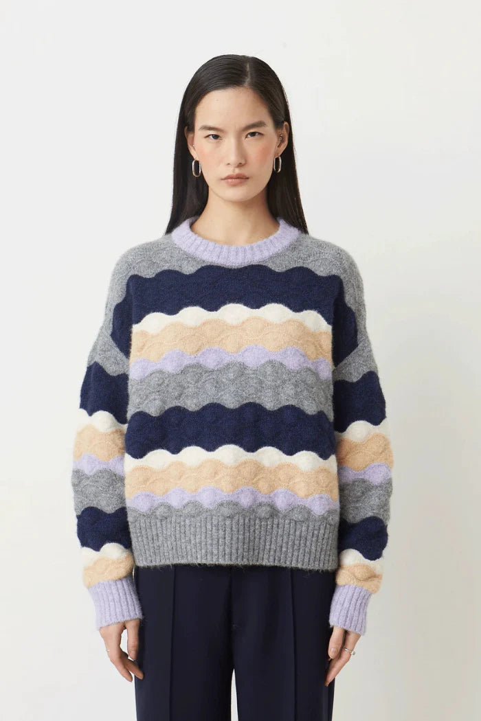 Woman wearing a colorful striped sweater against a white background