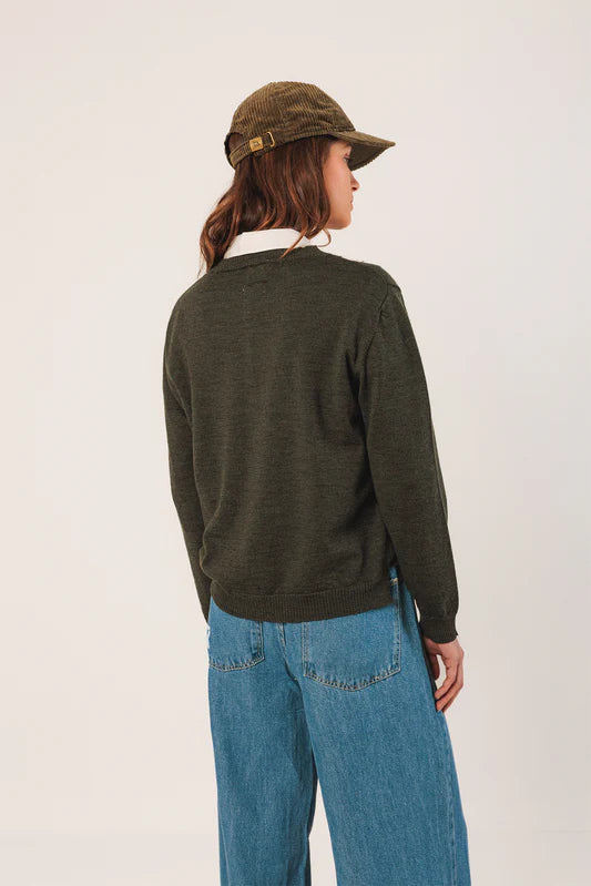 Person wearing a green sweater and blue jeans with a white background