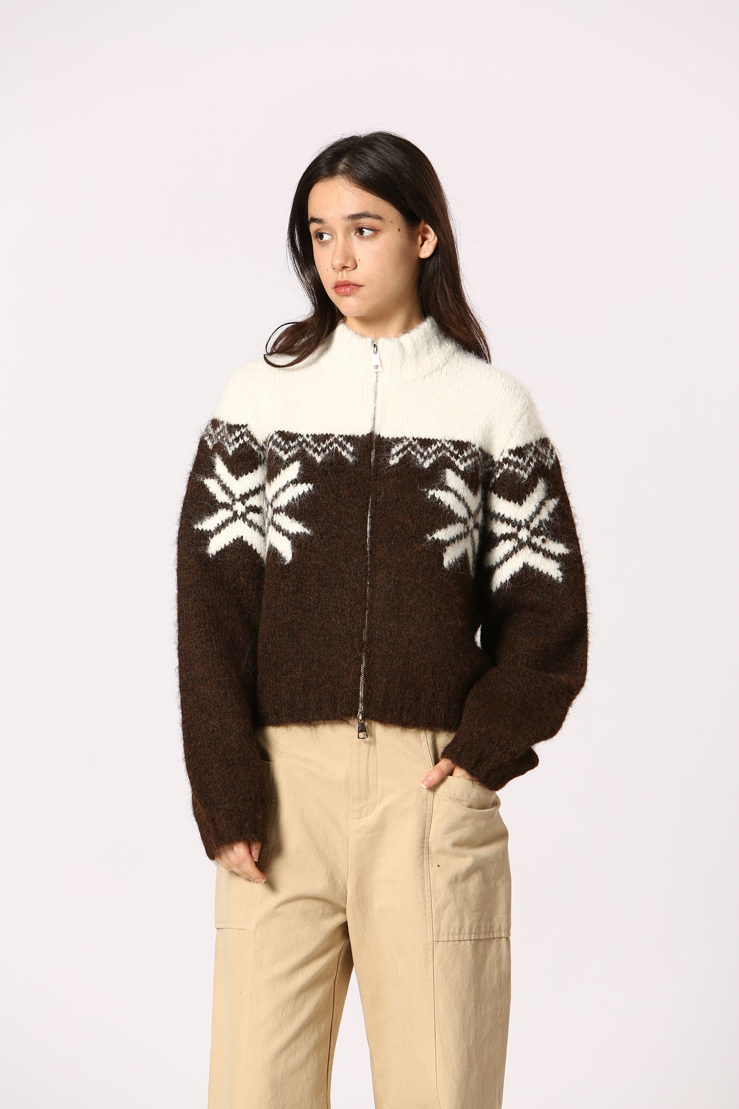 Person wearing a brown sweater with white patterns on a plain background