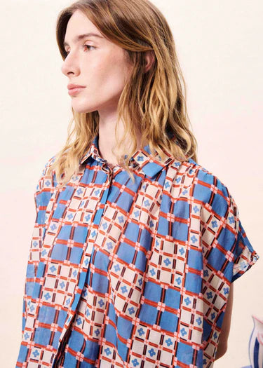 Person wearing a patterned shirt with a neutral background