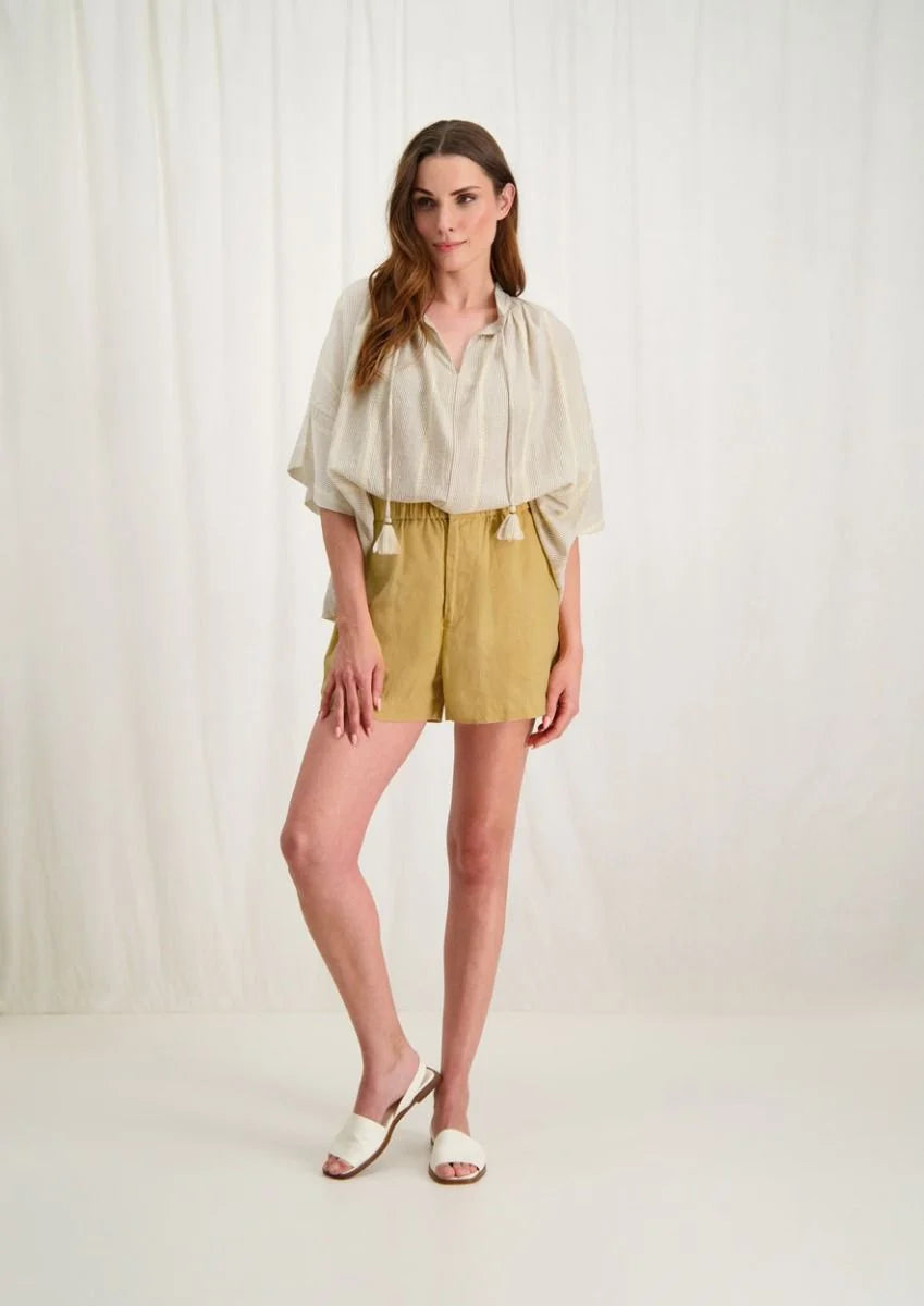 Introducing the Avril Blouse in Antique White by Circle of Trust. Made from soft 100% cotton, it's comfy and breathable for everyday wear. The loose fit and vertical stripe pattern give it a relaxed yet stylish vibe. With a V-neck and delicate strings, it's effortlessly charming. Plus, it has drop shoulders and wide sleeves for a comfy fit. Finished with tassel ties and subtle ochre accents, it's a versatile piece for any occasion. Pair it with denim shorts or a skirt for a casual look. 