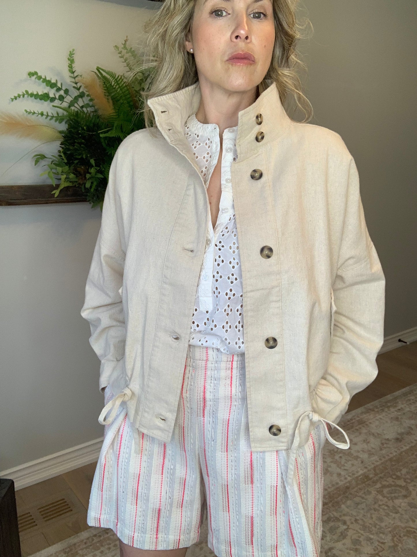 Introducing the Bibi Jacket by Circle of Trust. Made with a blend of linen and cotton, it's lightweight and comfy in a beautiful vanilla colour. With its loose fit and button-down front, it's easy to wear and style. The jacket has flap pockets and unique bat sleeves. Perfect for casual days out or running errands, or dress it up. It's a versatile addition to your wardrobe.