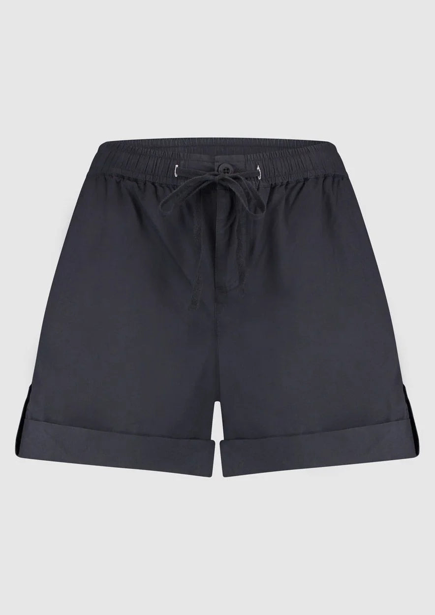 Introducing Circle of Trust's Mali Shorts in India Ink. Made of 100% cotton, these shorts are both comfy and stylish. They feature a loose fit, buttoned accents, an elastic waistband with a drawstring, and slit pockets for convenience. Perfect for any casual outing, these shorts offer comfort and versatility.
