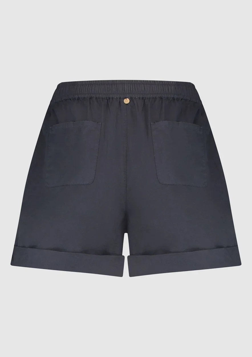 Introducing Circle of Trust's Mali Shorts in India Ink. Made of 100% cotton, these shorts are both comfy and stylish. They feature a loose fit, buttoned accents, an elastic waistband with a drawstring, and slit pockets for convenience. Perfect for any casual outing, these shorts offer comfort and versatility.