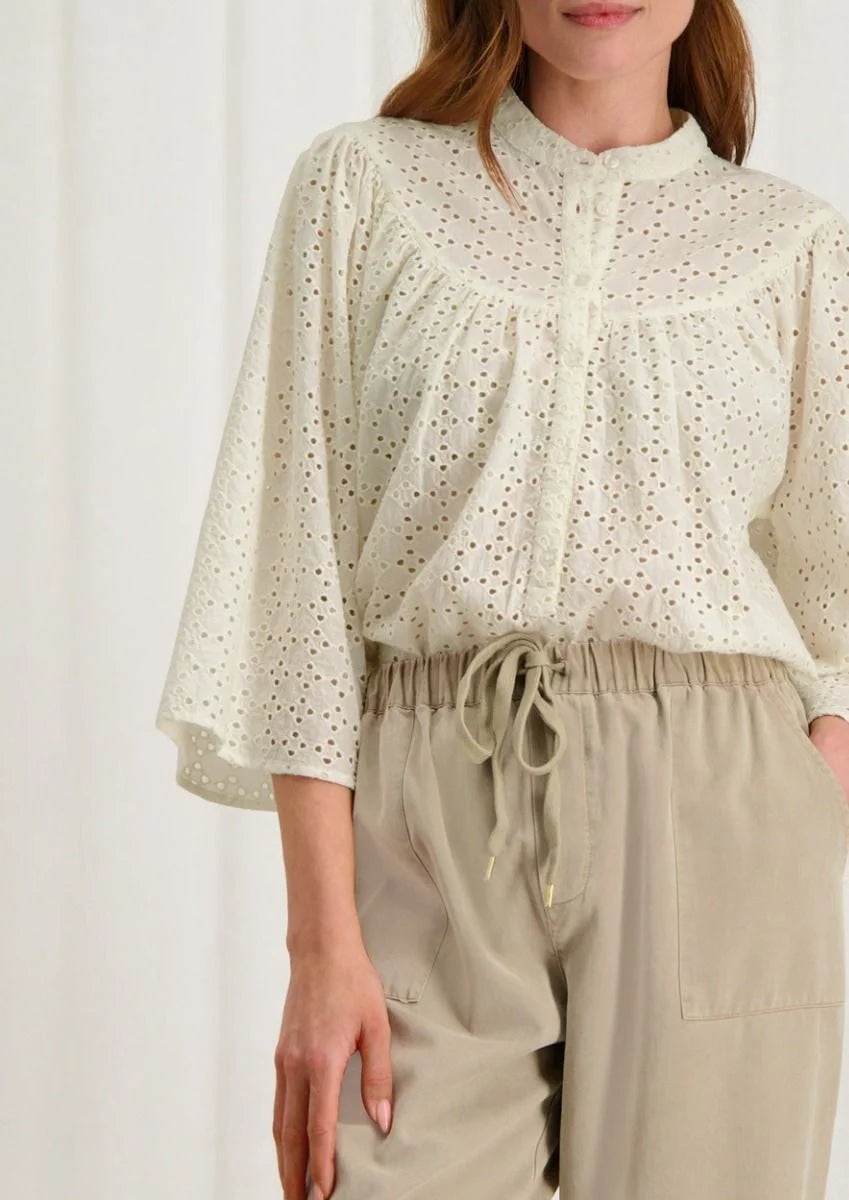 Introducing the Merlin Blouse by Circle of Trust in Antique White. Made from soft 100% cotton eyelet fabric, it's comfy and breathable. With its loose fit and wide 3/4 sleeves, it's effortlessly stylish. Featuring delicate embroidery, a classic crew neck, and a button placket, it's a versatile piece for any occasion. Dress it up or down, it's bound to be one of the prettiest blouses in your wardrobe.