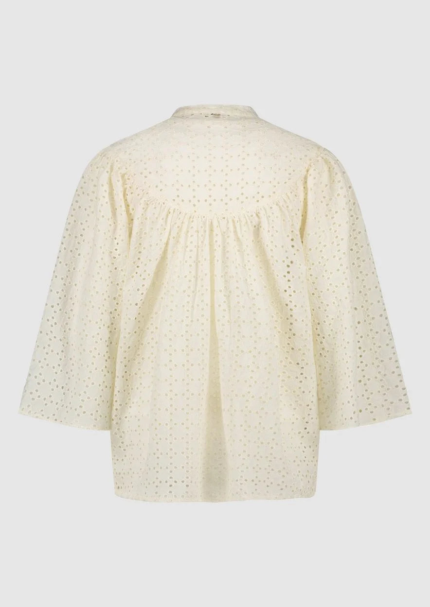 Introducing the Merlin Blouse by Circle of Trust in Antique White. Made from soft 100% cotton eyelet fabric, it's comfy and breathable. With its loose fit and wide 3/4 sleeves, it's effortlessly stylish. Featuring delicate embroidery, a classic crew neck, and a button placket, it's a versatile piece for any occasion. Dress it up or down, it's bound to be one of the prettiest blouses in your wardrobe.