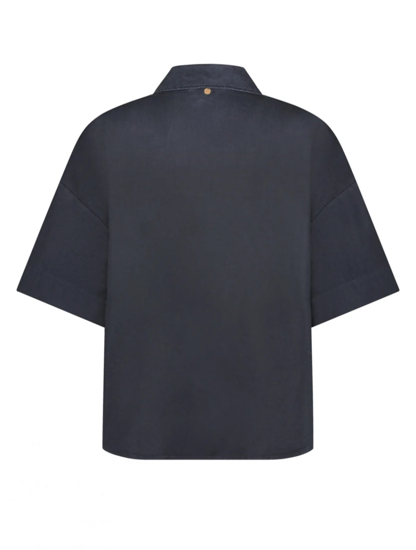 Introducing the effortlessly chic Ovi Blouse in India Ink by Circle of Trust, a wardrobe essential crafted from 100% cotton for unparalleled comfort and breathability. Embrace relaxed elegance with its oversized silhouette, exuding contemporary charm with every wear. This versatile piece features a flattering V-neckline and short sleeves, all tailored to perfection in soft, luxurious cotton. Elevate your ensemble with the understated sophistication of the Ovi Blouse, a timeless addition to your collection.