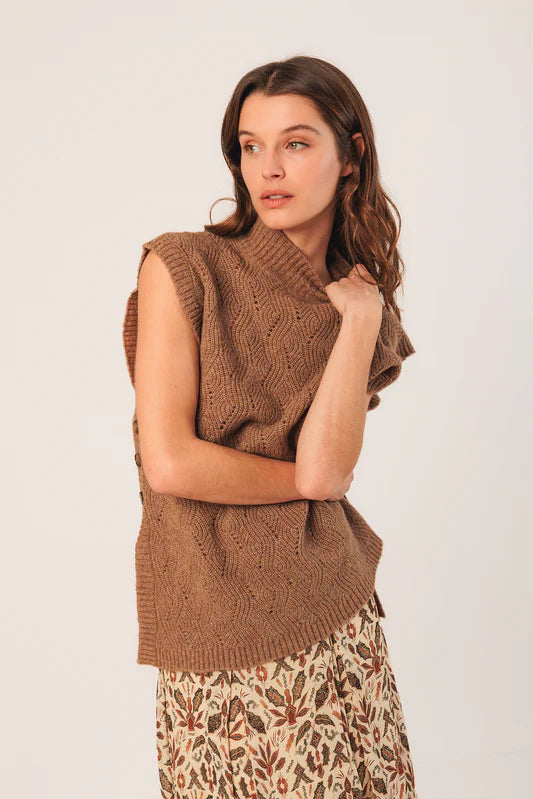 Woman wearing a brown knitted vest against a white background