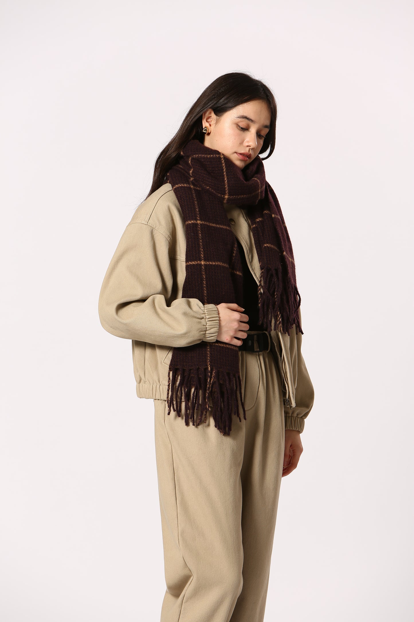 Person wearing a beige sweater and plaid skirt on a white background