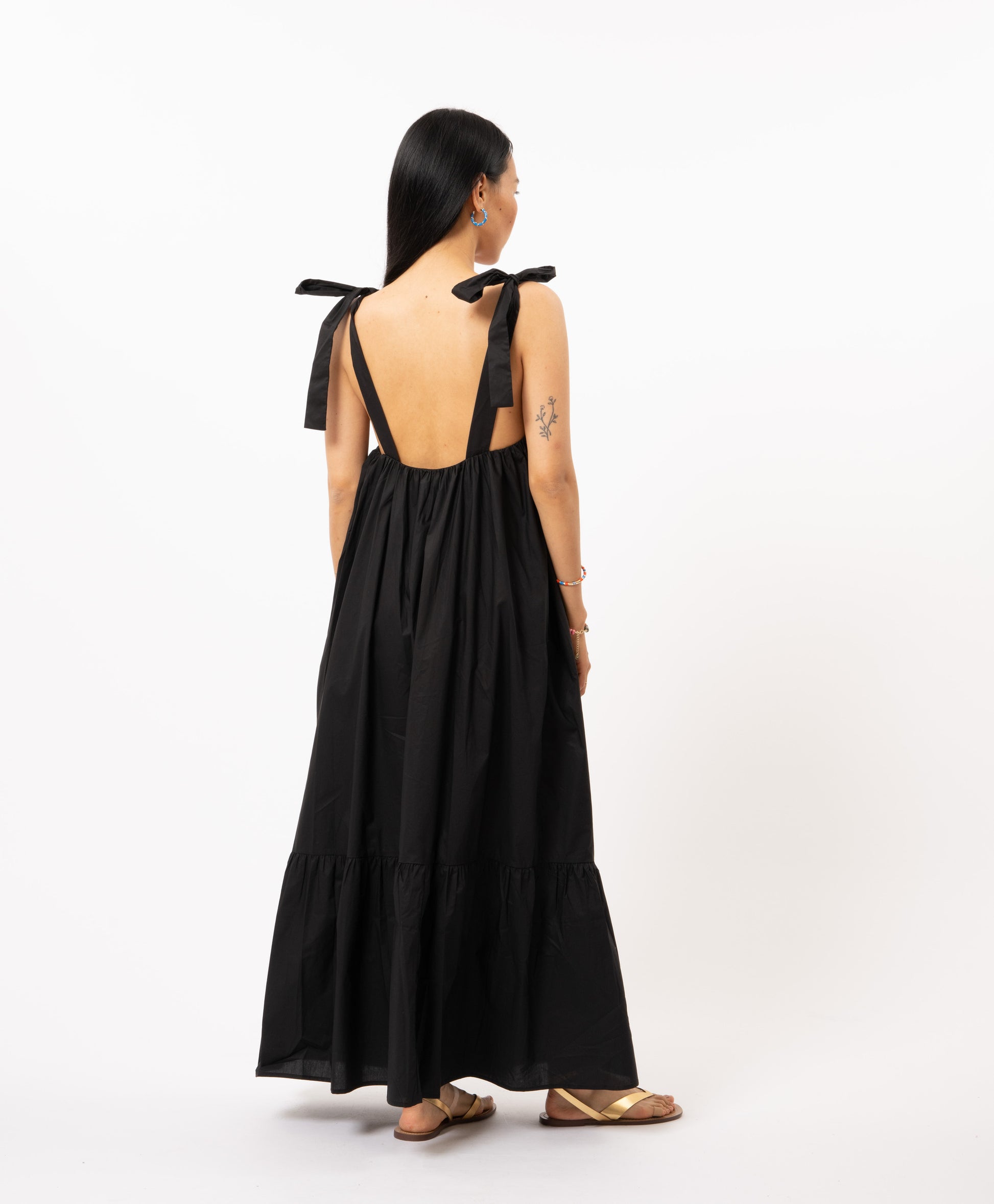 The Ceylia Dress in black by FRNCH is a versatile piece for any summertime occasion. With its fluid and flowing design, this long dress is ideal for any occasion. You can wear it tied around your shoulders or in a charming sailor style. Embrace the multiple ways to wear this tie band dress and create your perfect look.