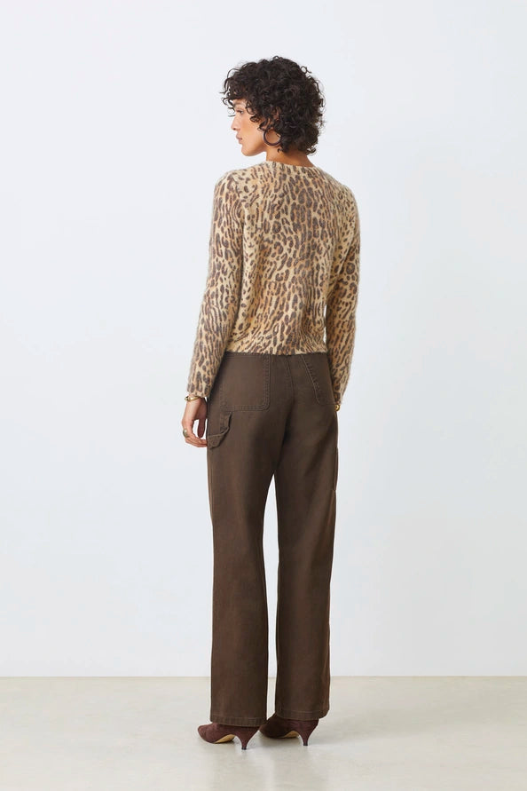 Person wearing a patterned blouse and brown pants on a white background