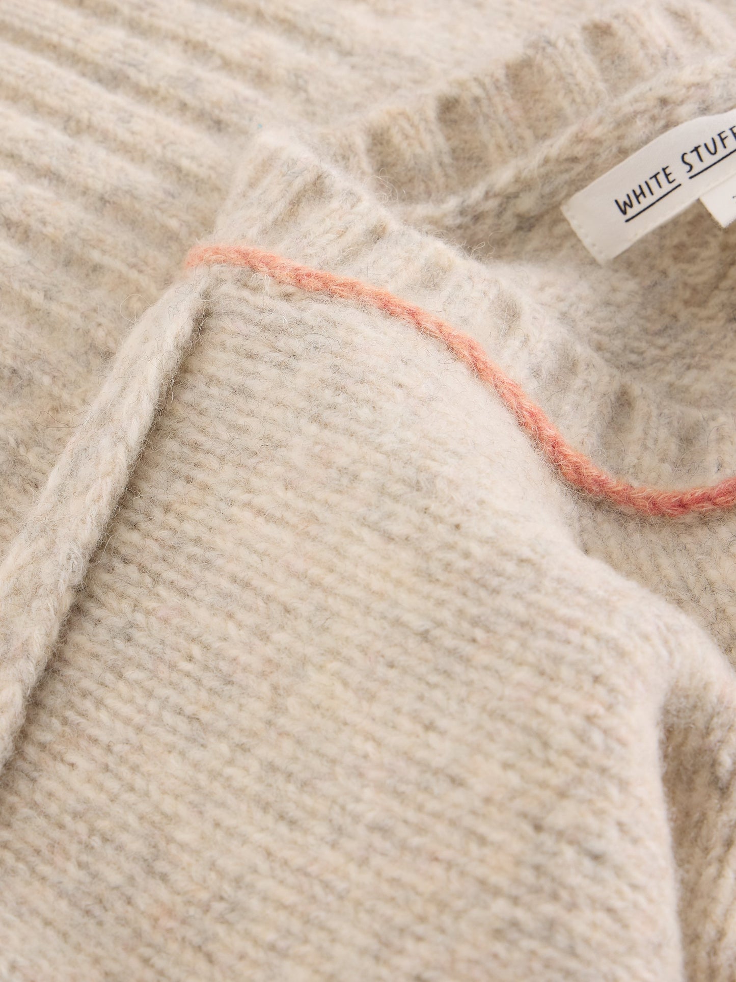 Close-up of a beige textured fabric with a brand tag.