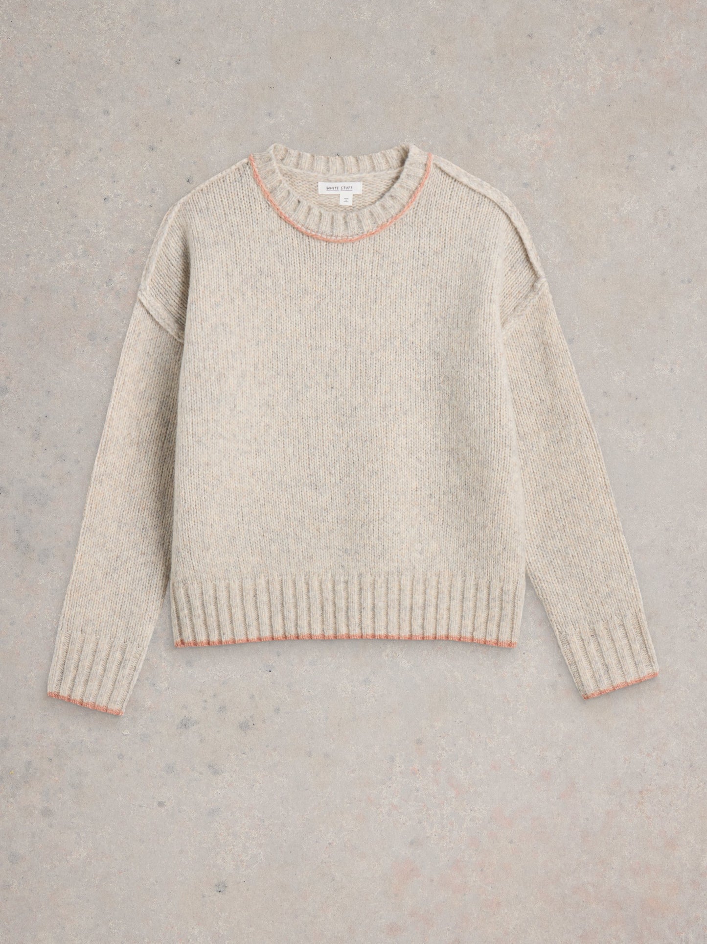 Beige sweater with pink trim on a gray background