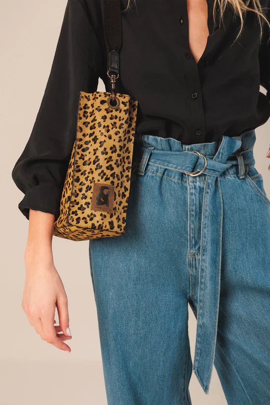 Person wearing a black shirt and blue jeans with a leopard print bag.