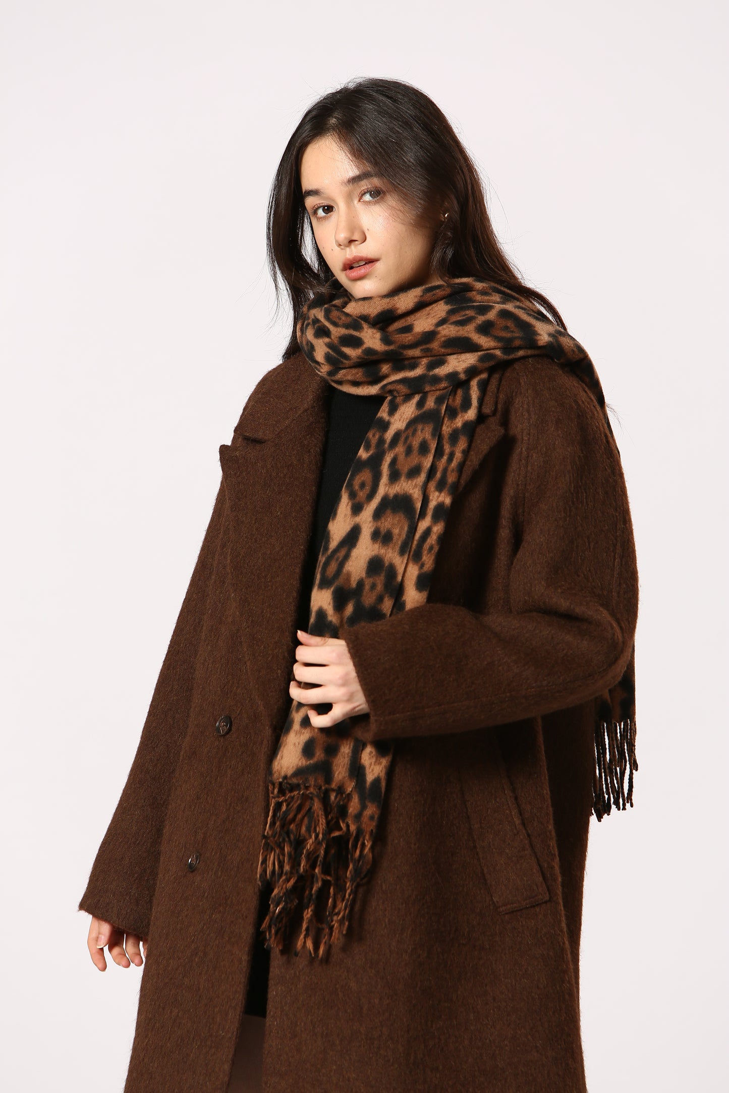 Woman wearing a brown coat and leopard print scarf on a white background