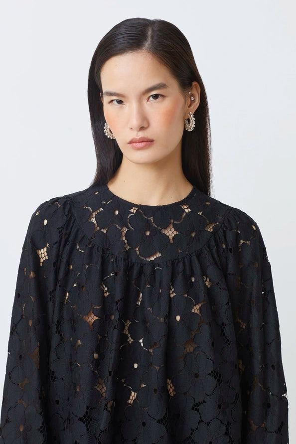 Woman wearing a black lace top against a white background