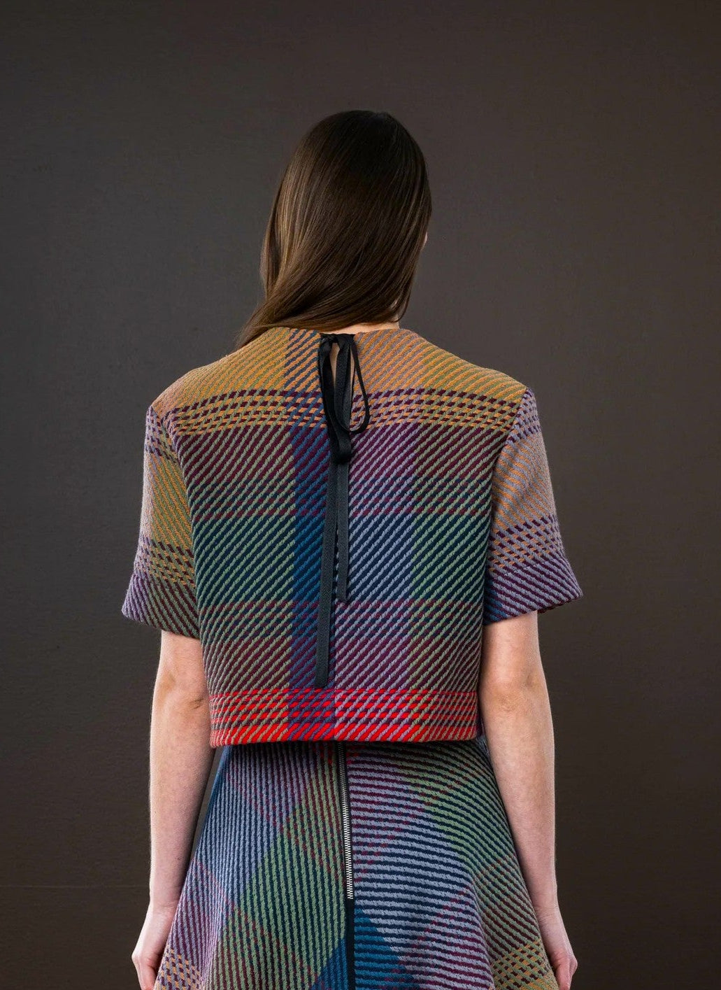 Woman wearing a colorful patterned outfit against a dark background