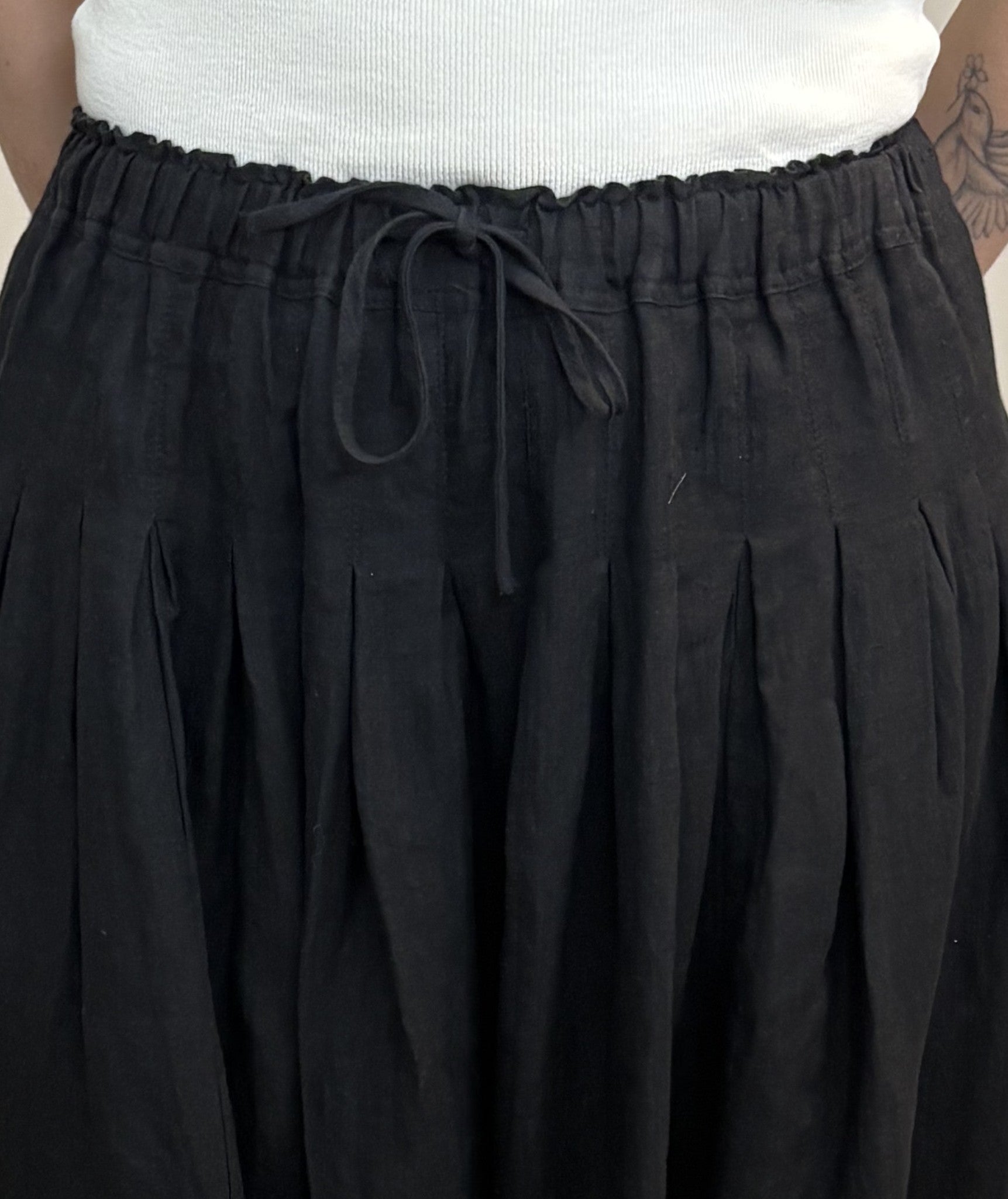 Get ready for some serious twirl action in the Jonie Skirt by Naif. Made from 100% linen, this black full skirt features an elastic waist with a tie front, creating the perfect fit. The beautiful pleating detail adds a touch of elegance to this playful piece.