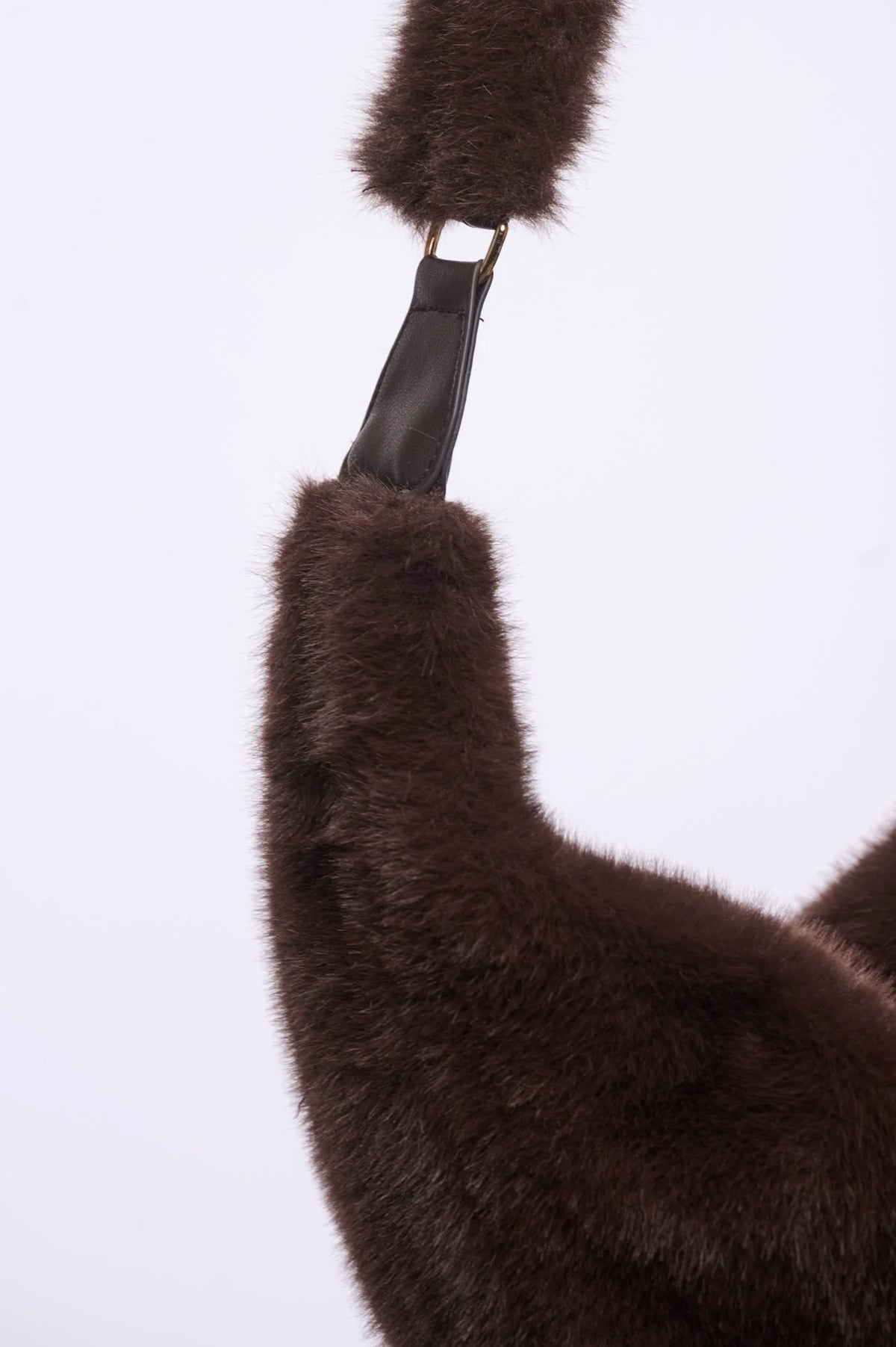 Rino & Pelle Nayla chocolate brown faux fur crescent crossbody bag worn across the body over a black wool coat