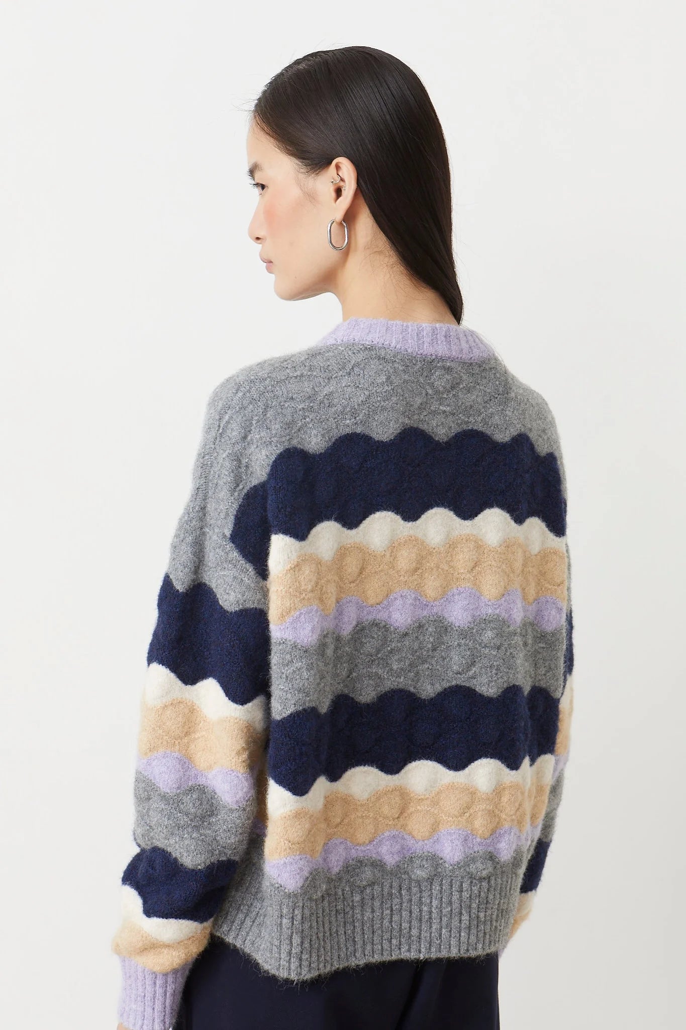 Woman wearing a colorful striped sweater on a light background