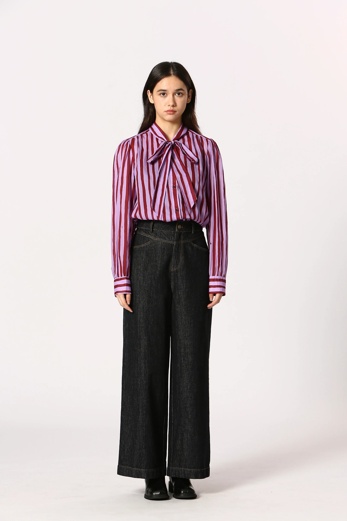Woman wearing a striped shirt and black pants on a white background