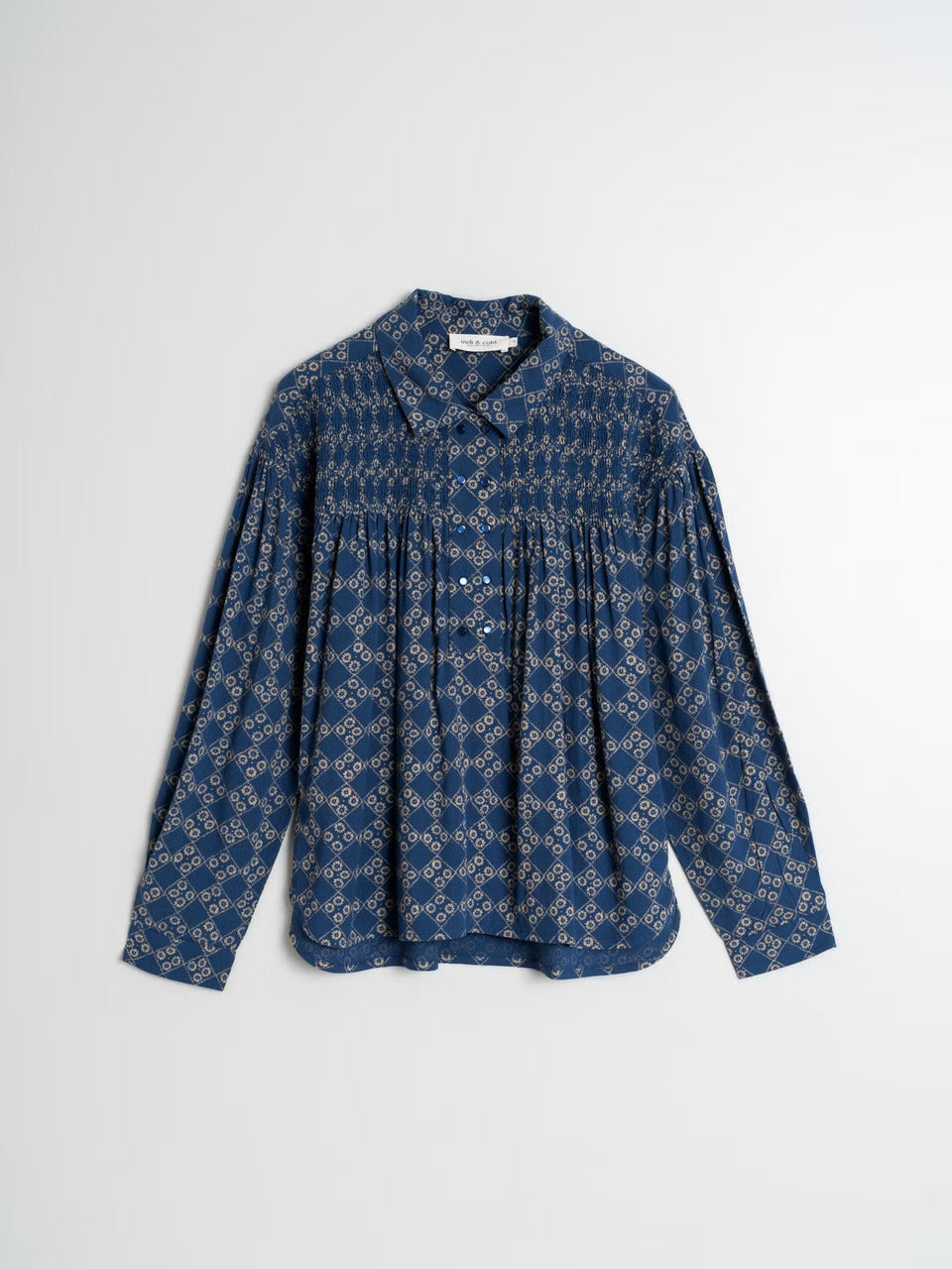 Get ready to turn some heads in our Smoke Detail Blouse by Indi & Cold! Made with soft woven viscose in a beautiful denim blue colour, this blouse features a unique beige geometric pattern and a flattering double button-down front. The rouched detailing across the chest and back adds a touch of fun and playfulness to your outfit. Easy to dress up or down, this is a must-have addition to your wardrobe!