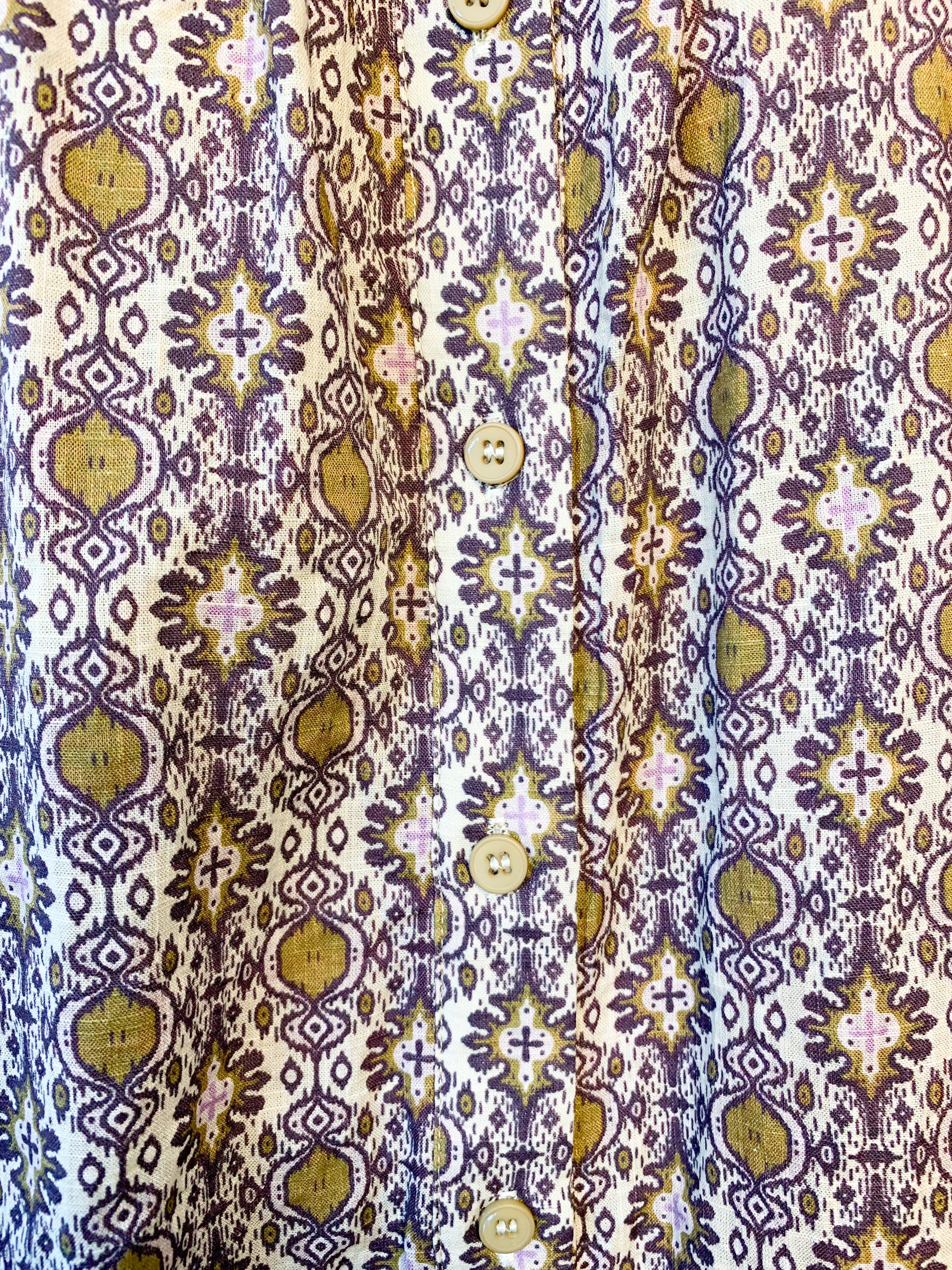 This Buttoned dress by the Korner features a timeless design with a classic round neckline and flattering long puffed sleeves that showcase the flared cut of the skirt, creating a flattering and comfortable silhouette. The geometric pattern in hues of purple with ochre accents is perfect for an autumnal look. lemon cyprus boutique