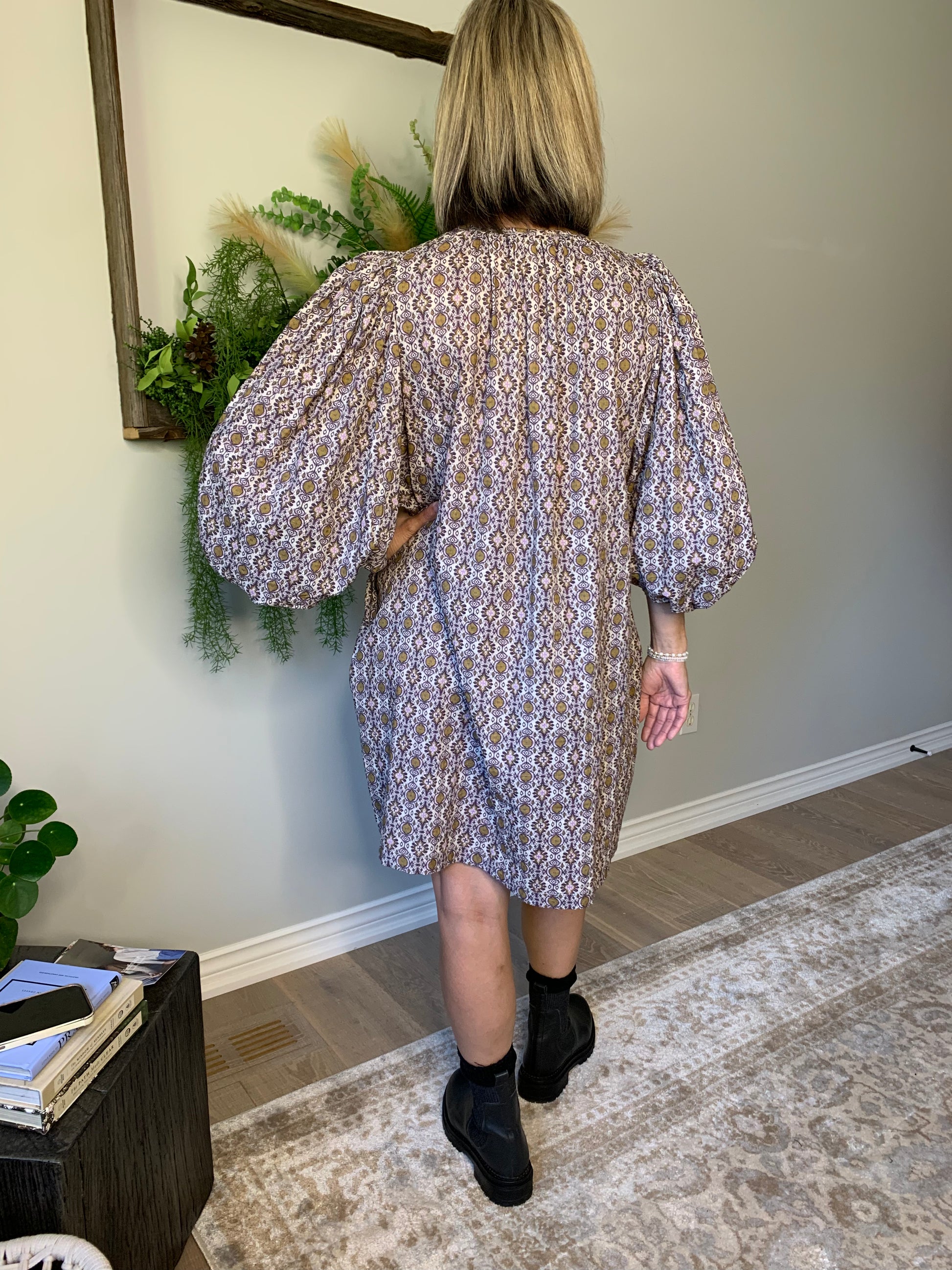 This Buttoned dress by the Korner features a timeless design with a classic round neckline and flattering long puffed sleeves that showcase the flared cut of the skirt, creating a flattering and comfortable silhouette. The geometric pattern in hues of purple with ochre accents is perfect for an autumnal look. lemon cyprus boutique