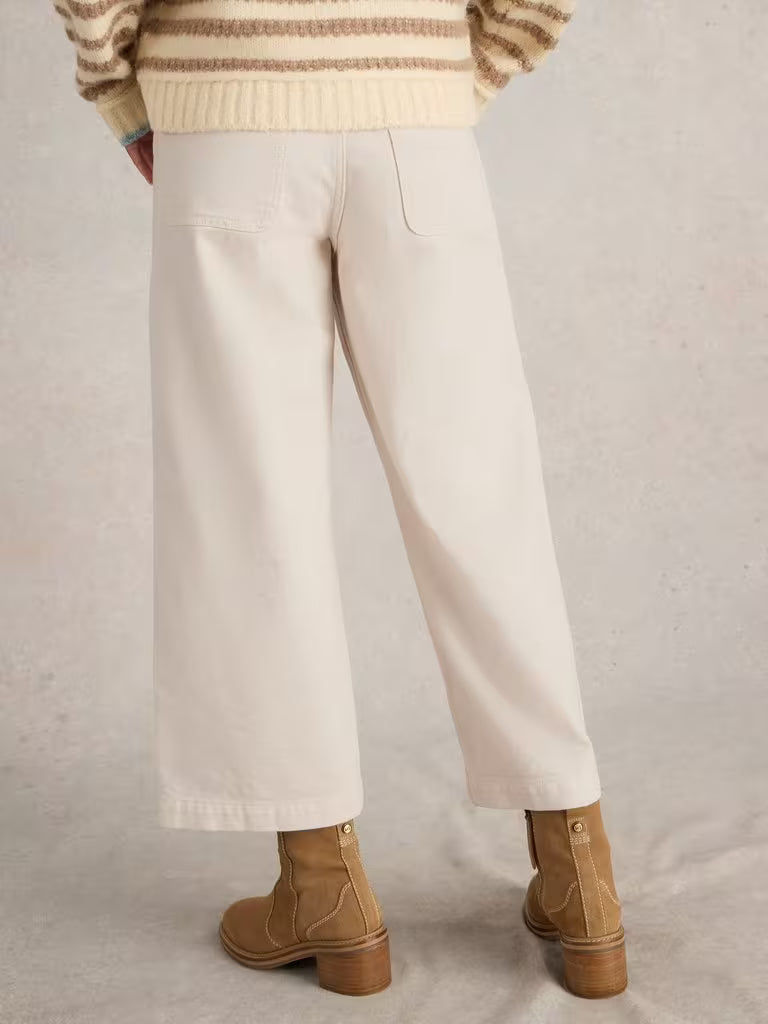 Person wearing beige pants and brown boots on a plain background