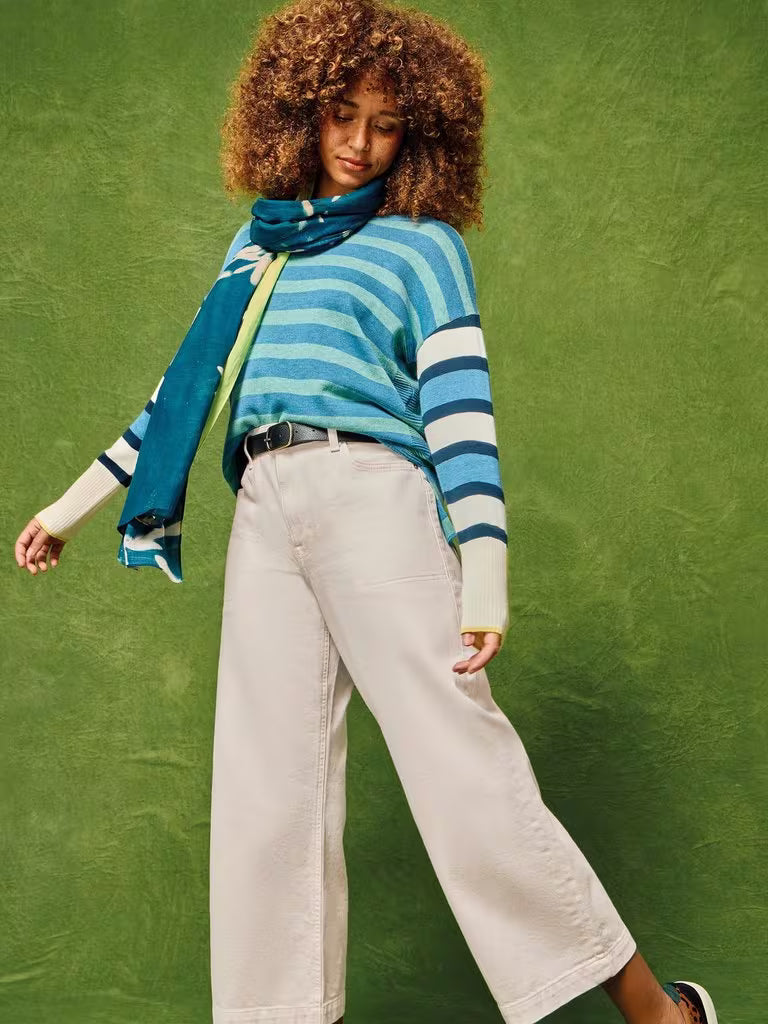 Person wearing a blue and white striped sweater with a scarf against a green background