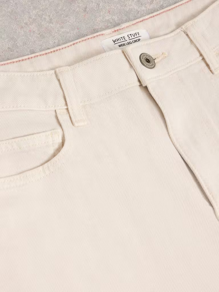 Close-up of beige pants with a brand label on a light gray background