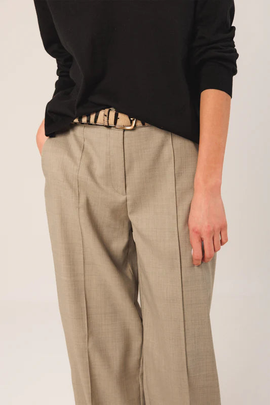 Person wearing beige pants and a black top with a white background