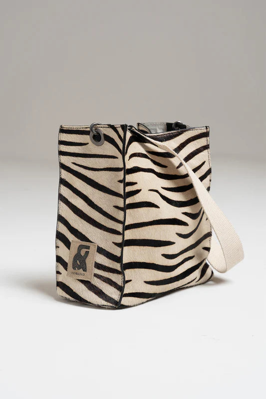 Zebra-patterned bag with a visible brand logo on a light gray background