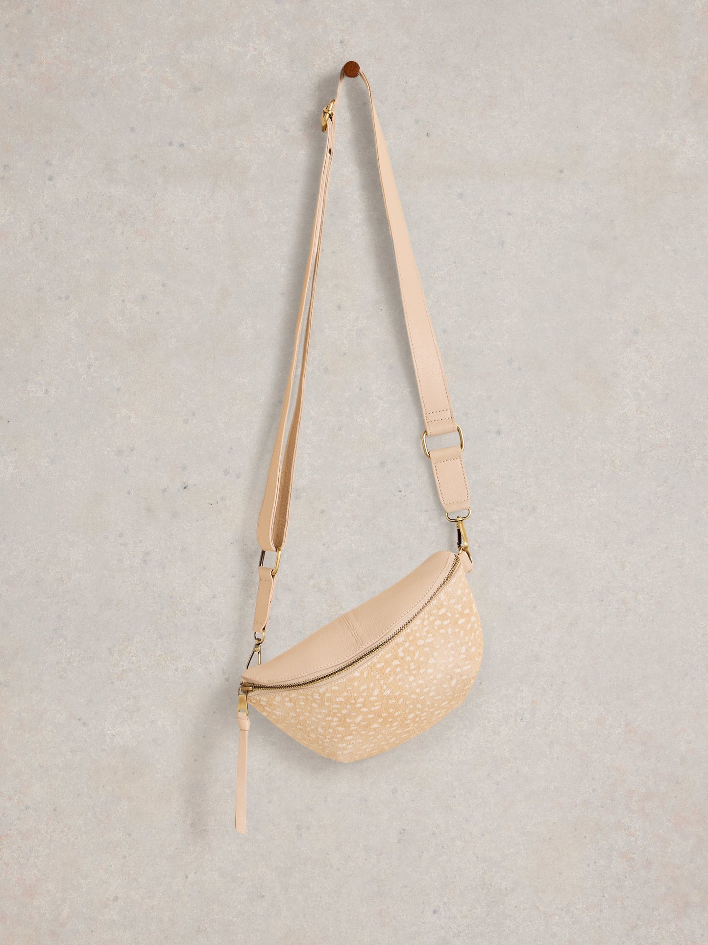 Beige woven crossbody bag on a light gray background