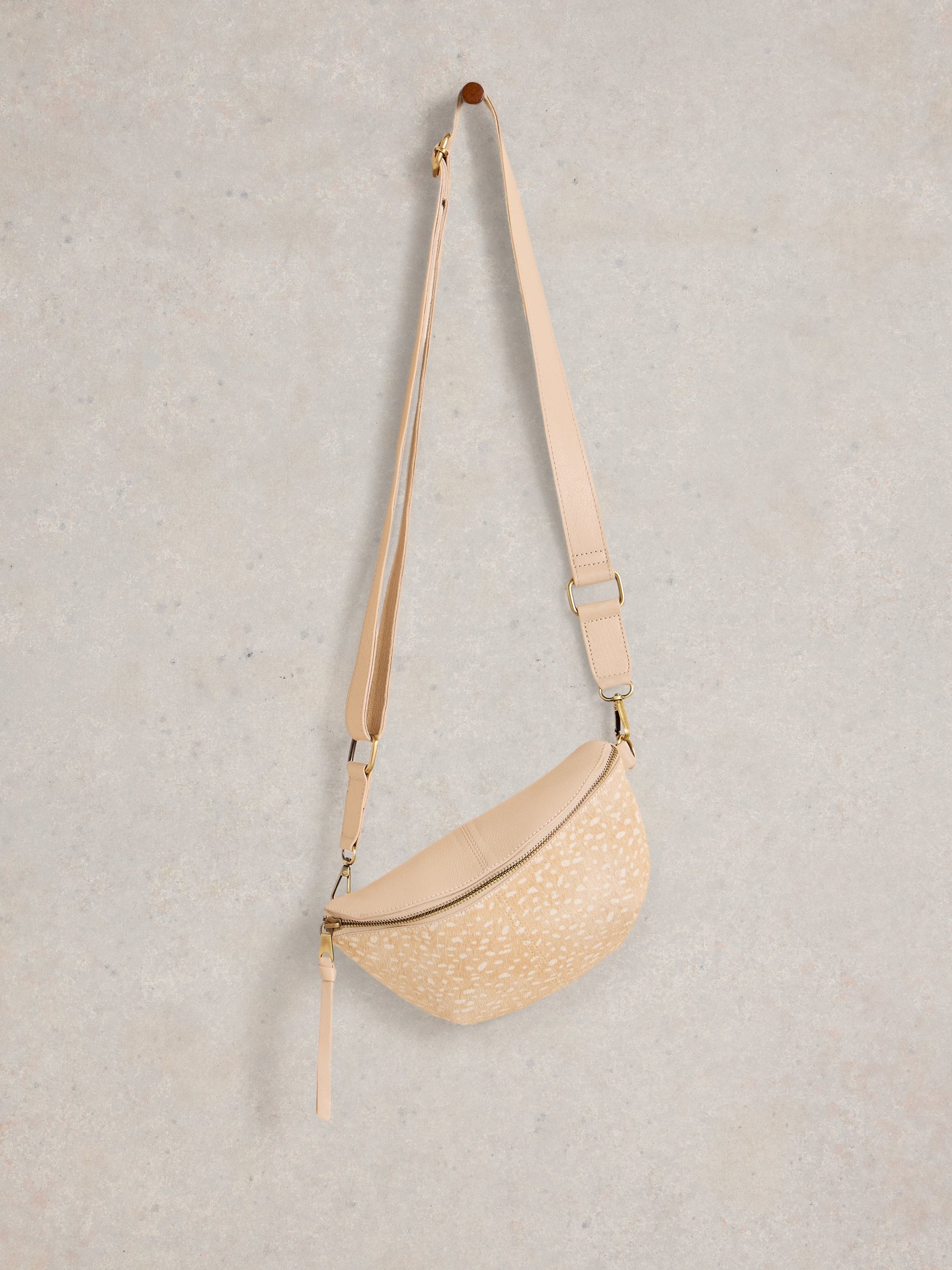 Beige woven crossbody bag on a light gray background